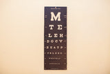 Lower section of antique Snellen eye chart, white letters on black board, with visible folds and wear.