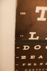 Close-up of the vintage Snellen eye chart's edge, revealing white text and wear.