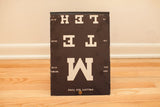 Folded antique Snellen's eye chart, heavy black board, white text, visible edge wear.