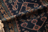 Folded Antique Persian Mehriban rug's Laleh Abbasi border, navy, raspberry, teal motifs, aged pile.