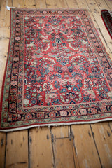 Vintage Sarouk rug corner highlighting intricate floral borders and brick red field with tattered end.