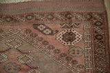 Anatolian rug corner showing running T-and-hook border and dusty rose field motifs.