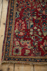 Detail of a Sarouk rug's meandering vine border and low-pile, cherry-red floral field.