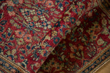 A vintage Sarouk rug runner rolled to display the soft texture of its cherry red pile.