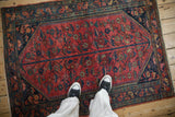Persian Lilihan rug corner with raspberry red field, navy border, and detailed vine motifs.