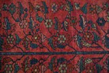 Close-up of Lilihan rug's raspberry red field, navy blue floral vines and border detail.