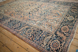 Distressed vintage Heriz carpet corner, dusty navy serrated leaf border and rose floral patterns.