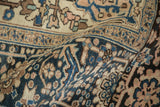 Curled texture of vintage distressed Heriz carpet showing dusty navy, rose, and pale coffee motifs.