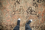 Persian Heriz rug with distressed pile, showing geometric designs in dusty rose and brown.