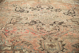 Softened distressed pile and geometric patterns of a vintage Heriz rug in dusty rose and brown.