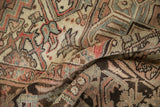 Distressed Heriz rug pile with short texture, showing muted rose, beige, and brown geometrics.