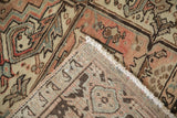 Distressed Heriz carpet showing geometric pattern, time-softened hues, and hand-knotted foundation and selvage.