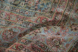 Distressed vintage Meshed carpet showing worn texture, faded raspberry, powder blue, and brown floral motifs.