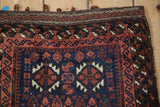 Close-up of the original latched macrame loops and ribboned border on an antique Belouch rug.