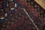Folded corner of an antique Belouch rug revealing its hand-knotted foundation and dense wool pile.