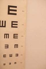 Lower portion of vintage eye chart with repeating black E's and '20 ft.' text on crinkled paper.