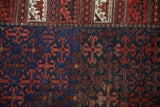 Junction of the antique Belouch rug's geometric border and its cobalt blue and red field.