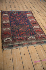 The tattered fringe and low pile of an antique Belouch rug seen from an angle.