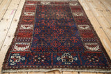 Full view of the antique Persian Belouch rug, angled to show the overall geometric pattern.