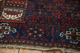 Detail of the pictorial border and worn foundation on a cobalt blue antique Belouch rug.