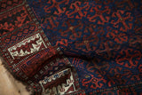 A folded corner of an antique Belouch rug highlighting the tattered edge and detailed border motifs.