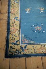 Peking rug corner: saffron yellow border, navy key-fret, dusty rose florals, tattered edge.