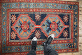 Corner of antique Northwest Persian rug with meandering vine border, geometric field, and blue abrashes.