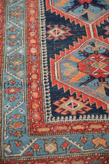 Tomato red vine border alongside serrated cobalt blue field on an antique Persian rug.