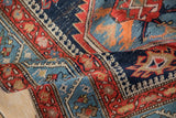 Curled antique Northwest Persian rug featuring serrated motifs, crab style renderings, and abrash in sapphire blue.