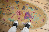 The unidirectional vase design in violet and jade on the golden field of an antique Art Deco rug.