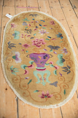 Angled view of an oval antique Art Deco rug showing its central vase design and floral sprays.