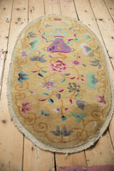 Angled view of an oval antique Art Deco rug featuring its full vase and floral pattern.