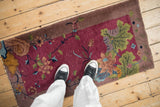 Antique Chinese Art Deco runner in burgundy with pictorial lotus, showing shoes for scale.