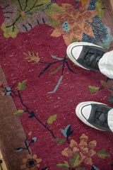 Pictorial floral motif on a burgundy Chinese Art Deco rug showing visible white knots.