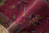 Art Deco rug's curled edge reveals textured mauve pile, floral motifs, and white knots.