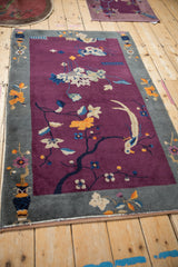 Antique Art Deco rug border detail: stylized vase, tangerine flowers, deep violet field.