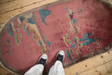 Antique Chinese Art Deco rug with dusty blush field, pictorial landscape design, and feet.