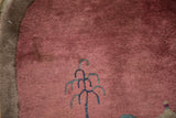 Faded cochineal red pile of an antique Art Deco rug, showing blue-green tree motif.