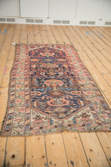 Geometric palmettes and finned blossoms on the antique Malayer runner's cobalt field, showing wear.