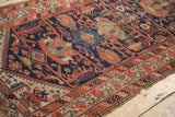 Antique Malayer runner detail: worn geometric border, tattered edge, faded red, blue, ivory.