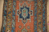 Close-up of the geometric medallion in sapphire blue and jade green on a madder red field.