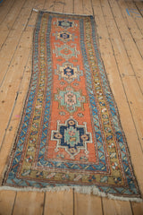 Angled view down the length of an antique Persian runner, showing its column of geometric medallions.