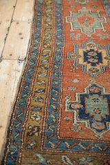 Close-up view of the antique rug's geometric border, highlighting the hand-knotted pile and side selvage.