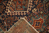 Vintage Karaja rug corner lifted, revealing its tattered fringe, foundation, and vibrant geometric patterns.