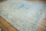 Distressed vintage Mehrivan carpet showcasing worn ivory and powder blue plant motifs.