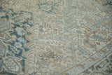 Distressed texture of a vintage Mehrivan rug with ivory, blue, and coffee brown plant motifs.