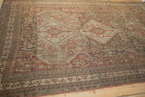 Distressed vintage Shiraz carpet corner, showcasing geometric floral blossoms and multiple border bands in earthy tones.