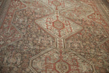 Distressed geometric floral and pinwheel motifs on a vintage Shiraz rug, with brown and ivory tones.
