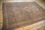 Distressed vintage Shiraz carpet showing geometric floral motifs and a hand-finished selvage.