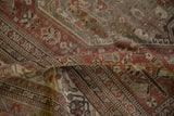 Distressed texture and geometric floral patterns on vintage Shiraz carpet.